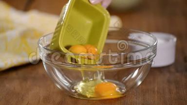 靠近站在厨房桌子旁的女人，用<strong>鸡蛋</strong>把糖倒入深盘子里，然后用<strong>搅拌</strong>机<strong>搅拌鸡蛋</strong>。